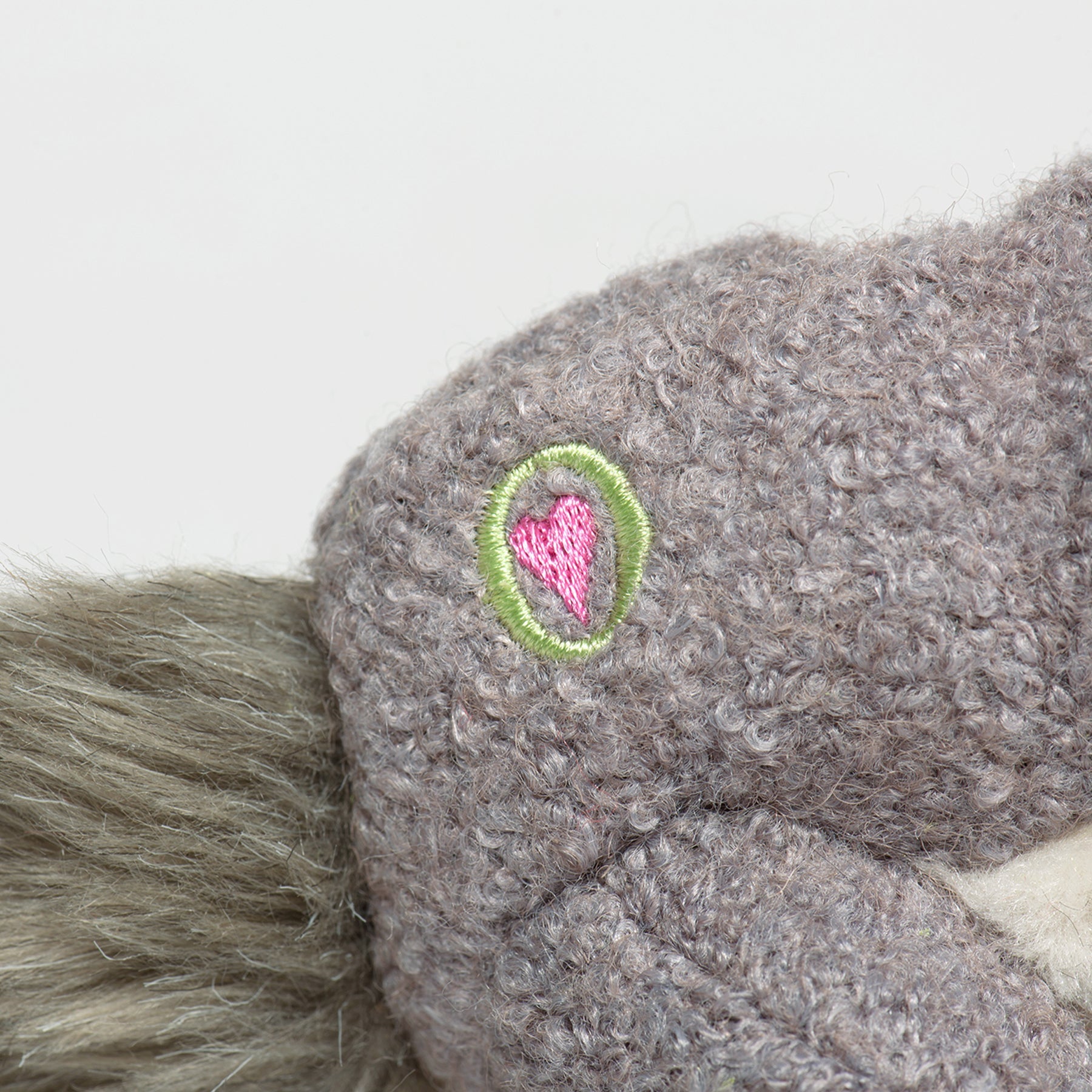 Close up image of the HuggleGroup logo one the right side of the Fellar Squirrel plush dog toy.